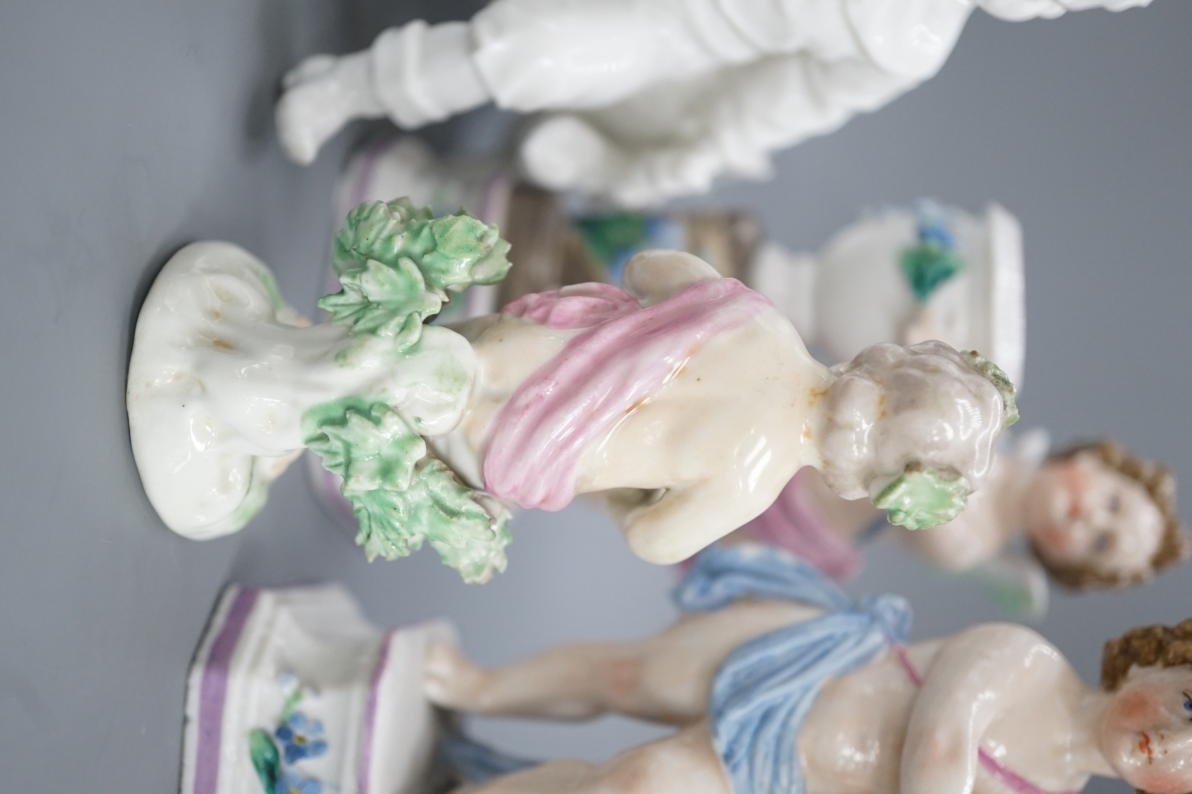 A pair of Continental porcelain cherub candlesticks, 13.5cm, a figural bonbon and a Derby figure